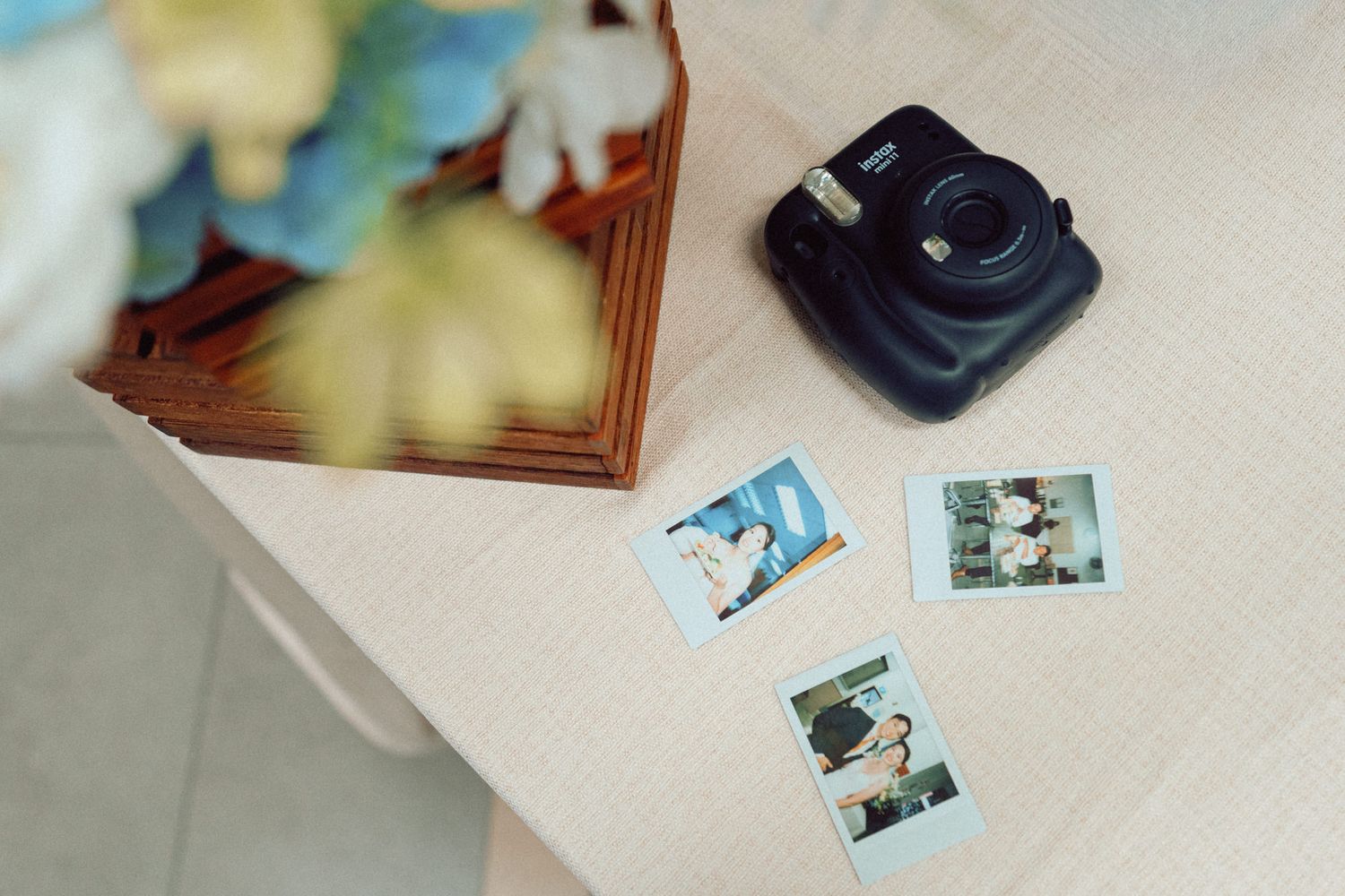 An instant camera with printed photos displayed on a light-colored surface.