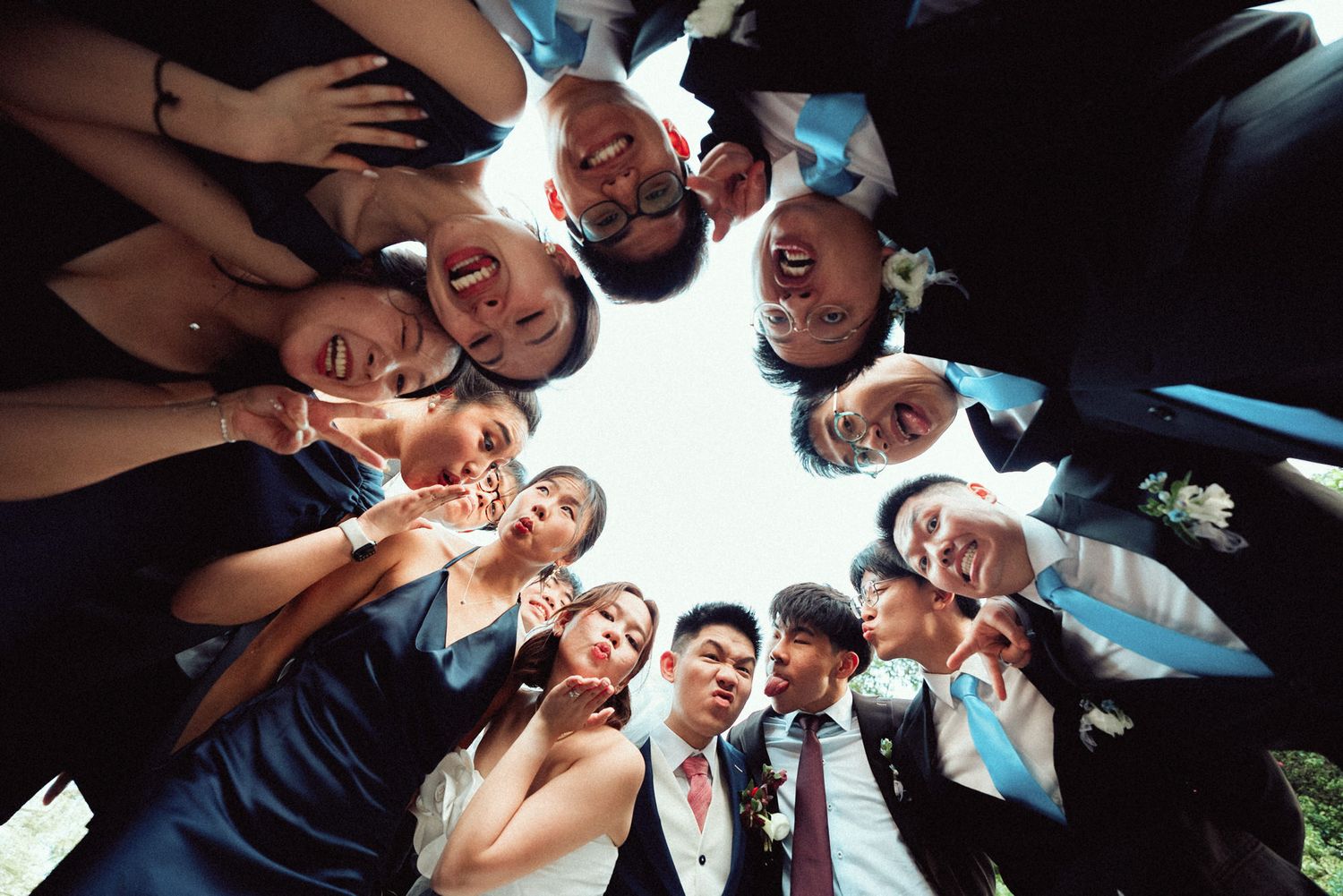A group of people huddle together in a circle formation looking down at the camera from above.