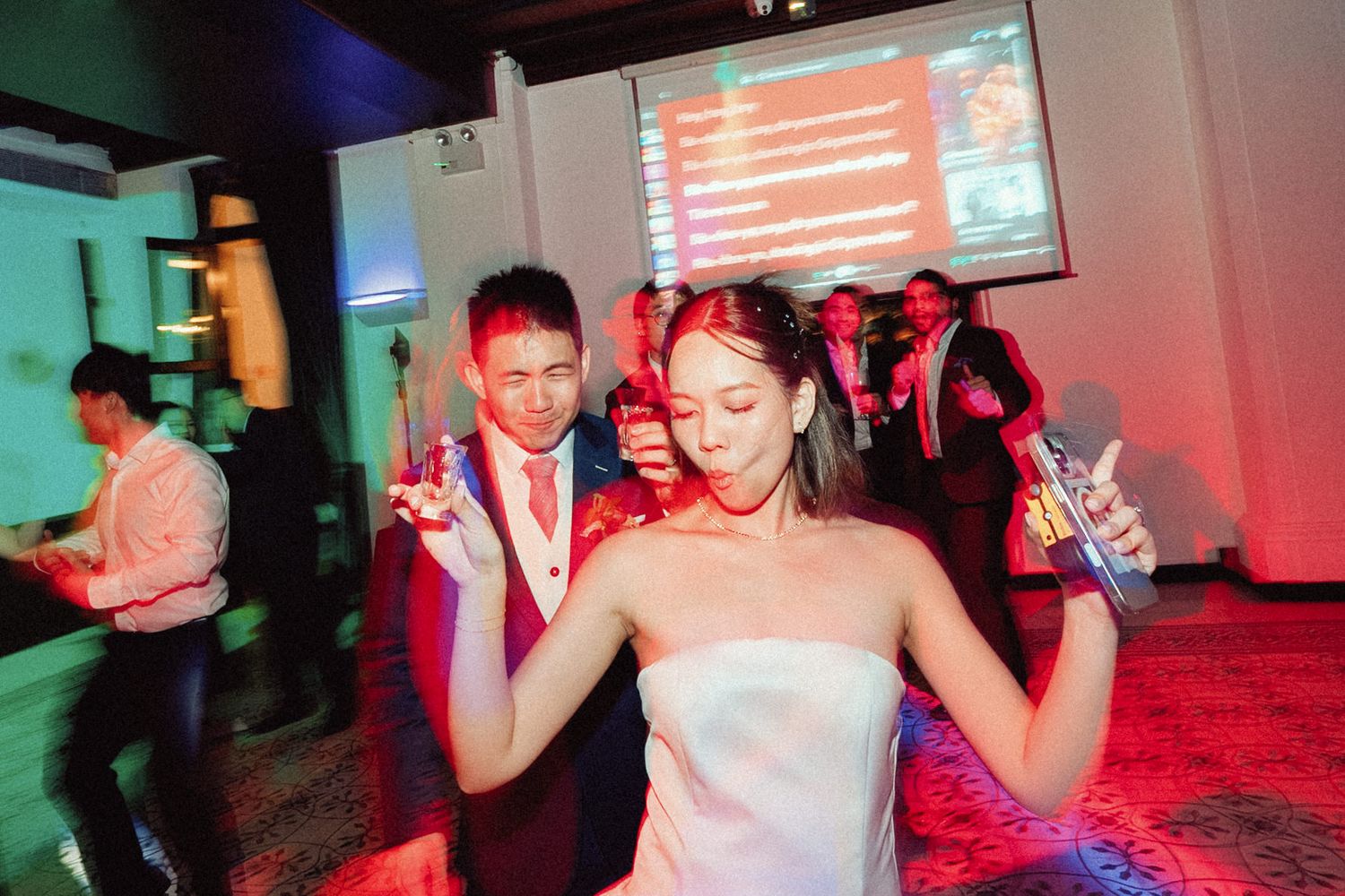 People dancing and socializing at a nightclub with red and blue lighting effects.