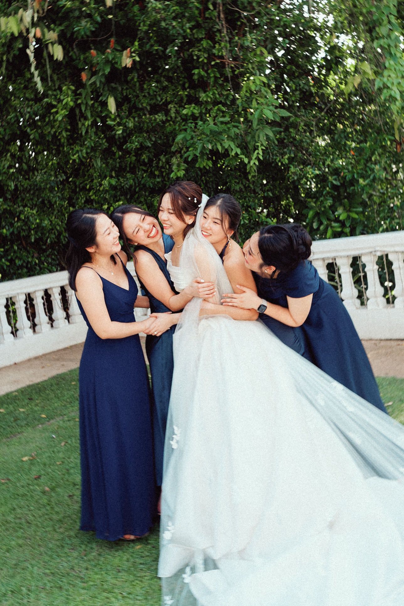 A sequence of candid wedding party photos showing bridesmaids in navy dresses sharing joyful moments with the bride in white.