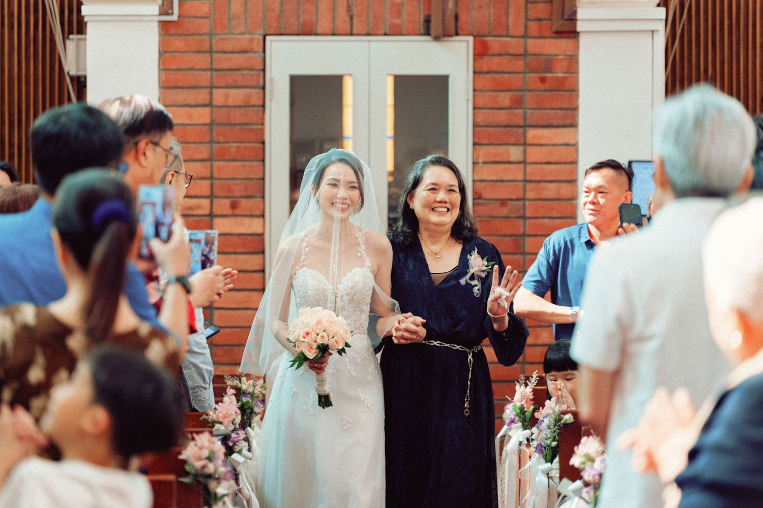 Wedding guests celebrate joyfully in a brick church with white columns during a ceremony.
