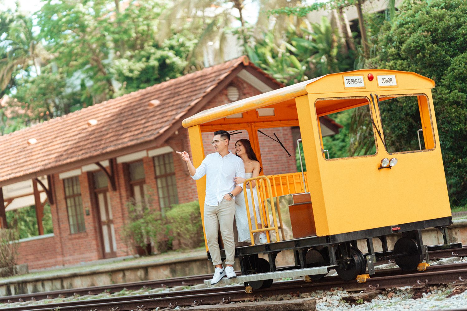 Bright orange rail car on train tracks surrounded by lush greenery.