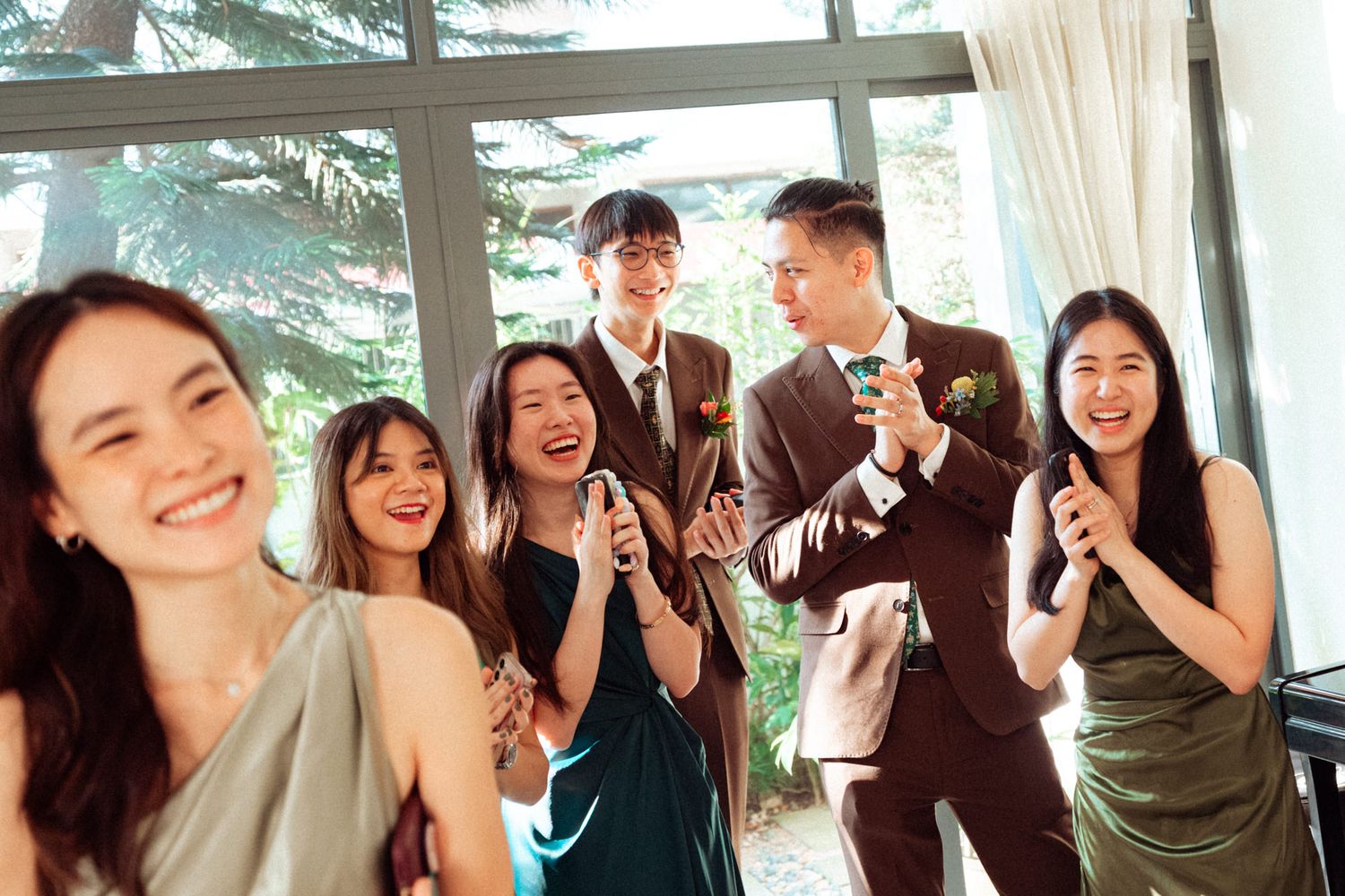 Group of elegantly dressed young adults smiling and celebrating together at a formal event or wedding reception.