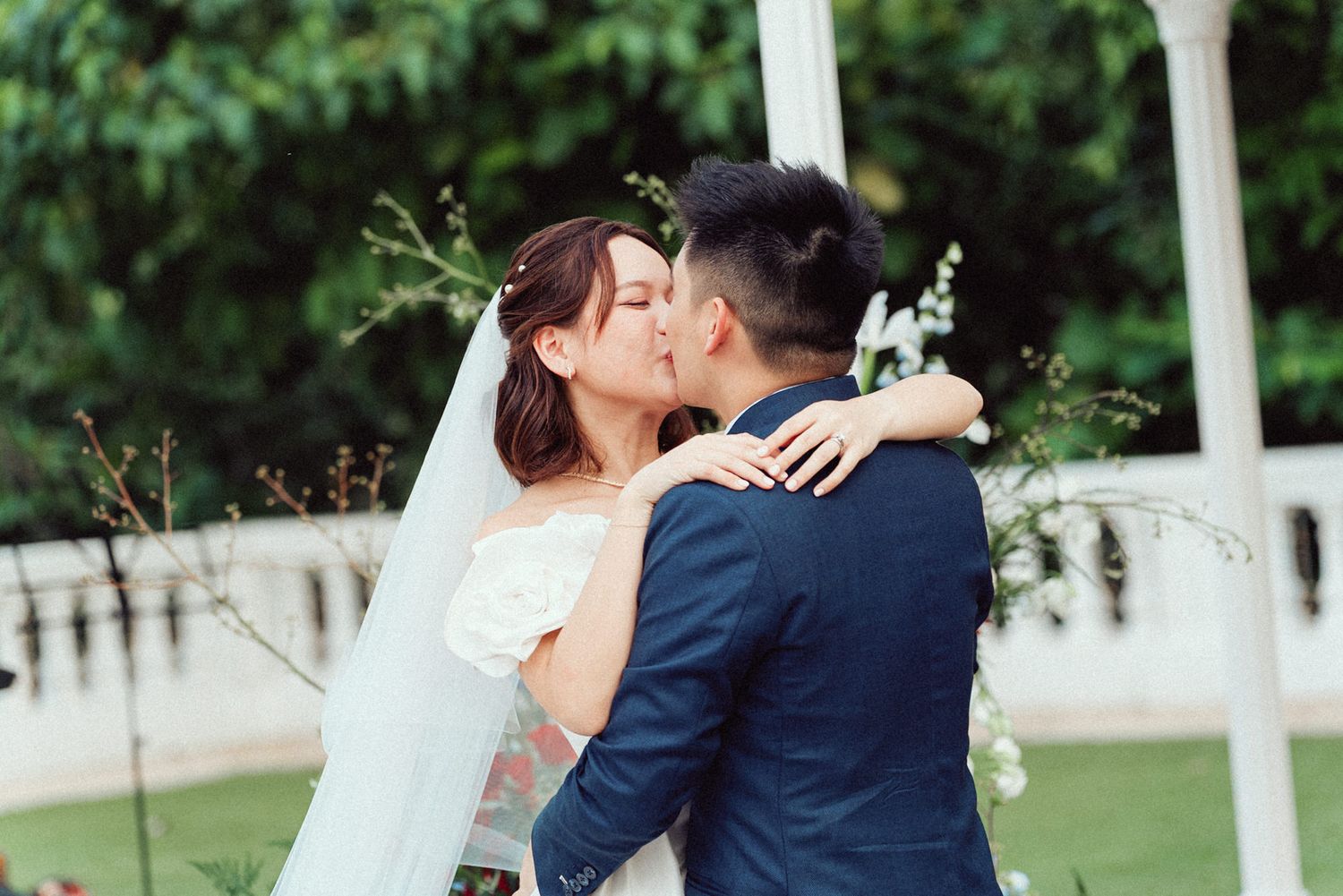 A couple shares romantic moments in a garden setting during their wedding photo session.