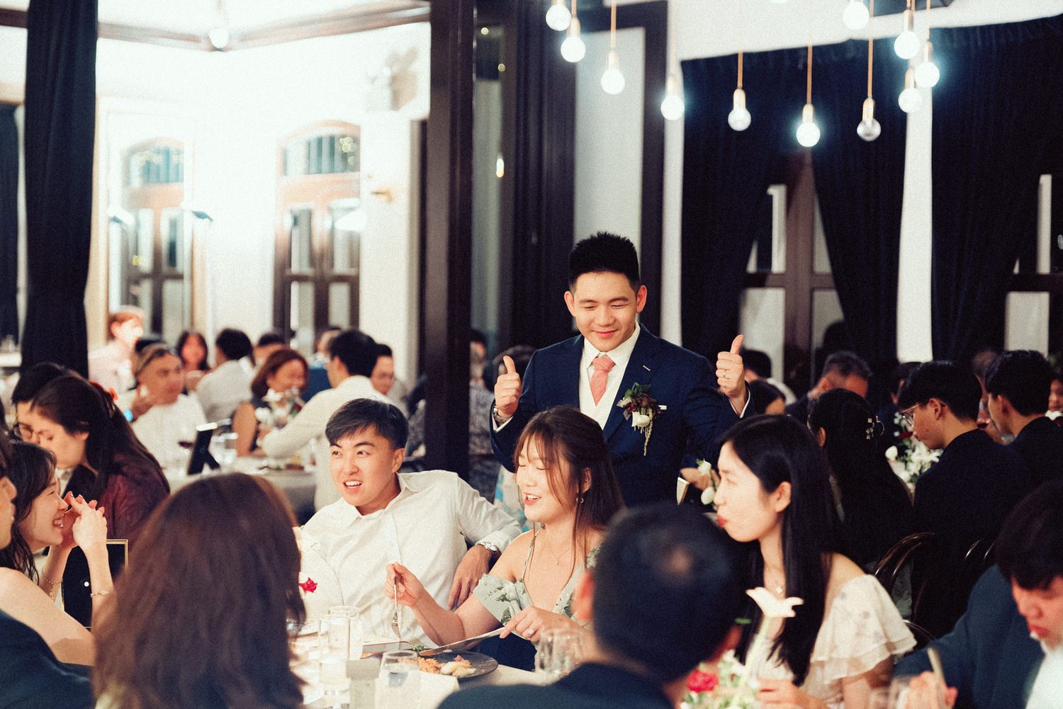 Guests enjoy a formal dinner gathering in an elegant restaurant with pendant lighting and white tablecloths.