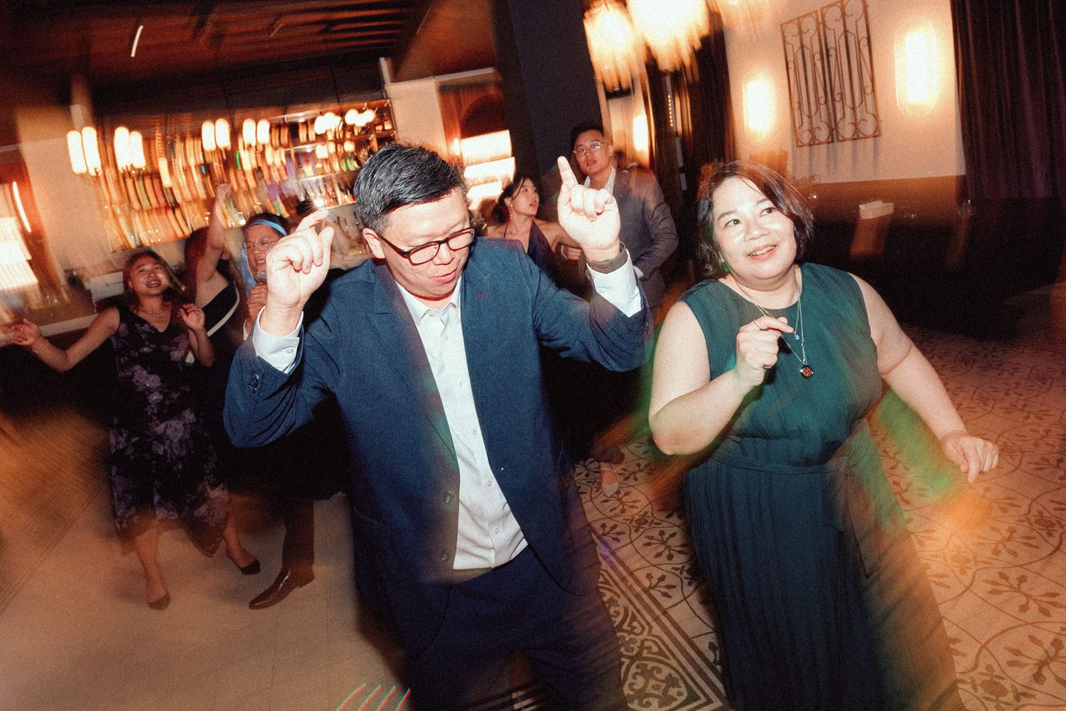 People dancing together in a warmly lit ballroom during what appears to be a social dance event.