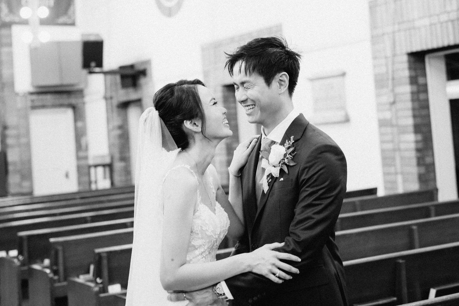 Black and white photo of couple sharing intimate moment in church pews.