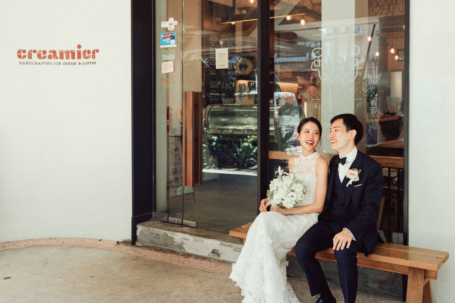 Wedding couple walking past storefront with 'creamier' signage visible.
