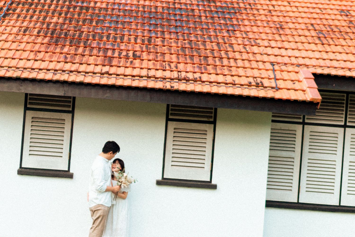 A row of terracotta-roofed buildings with white walls and shuttered windows stretches along a residential street.