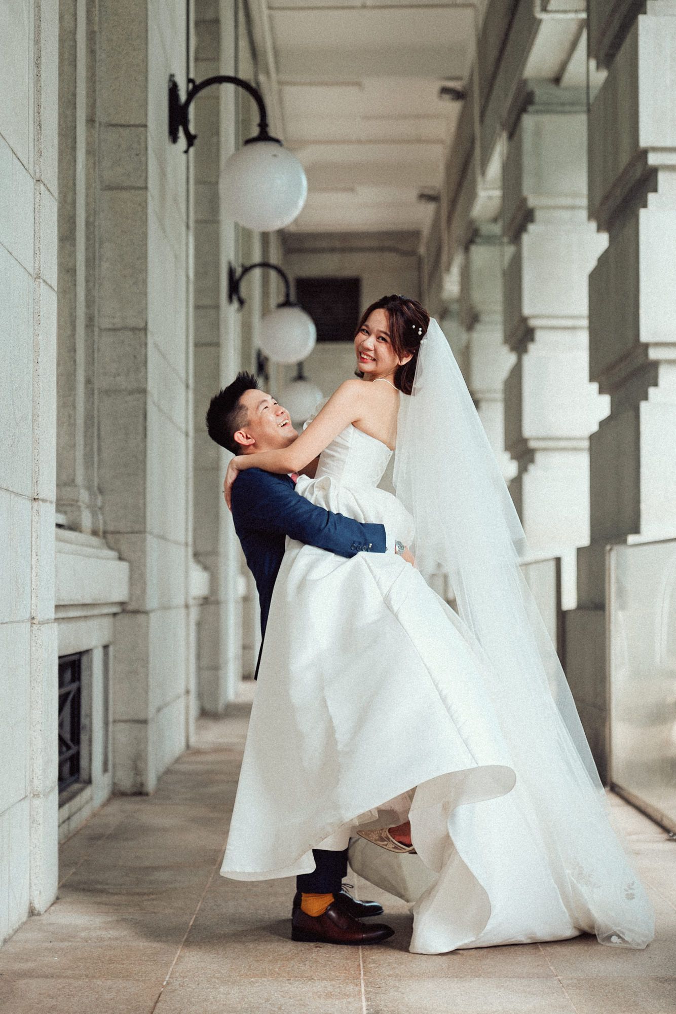 A playful wedding photo sequence showing a couple in white dress and suit dancing in a columned hallway.