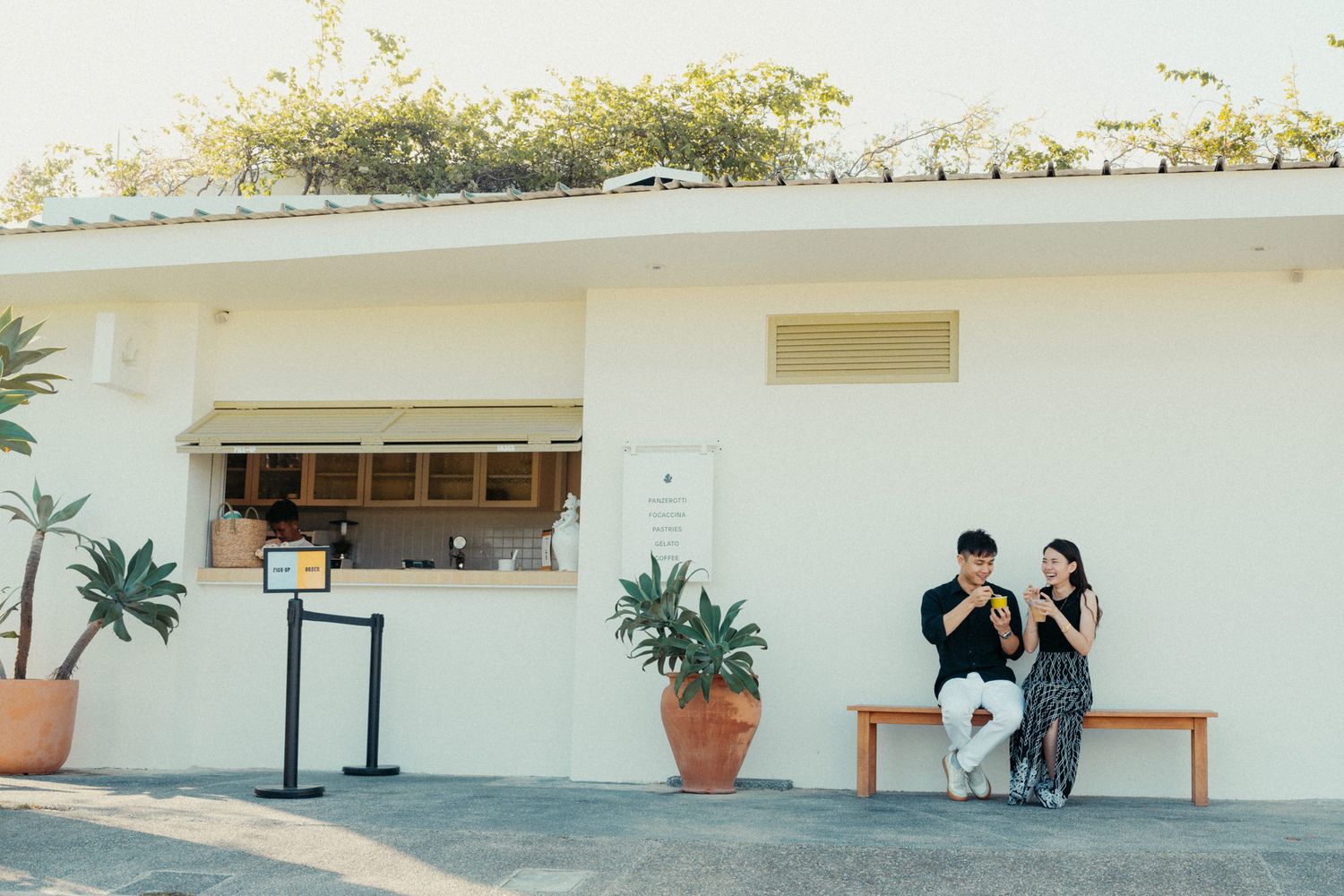 White building exterior with potted plants and benches creating a minimalist scene.
