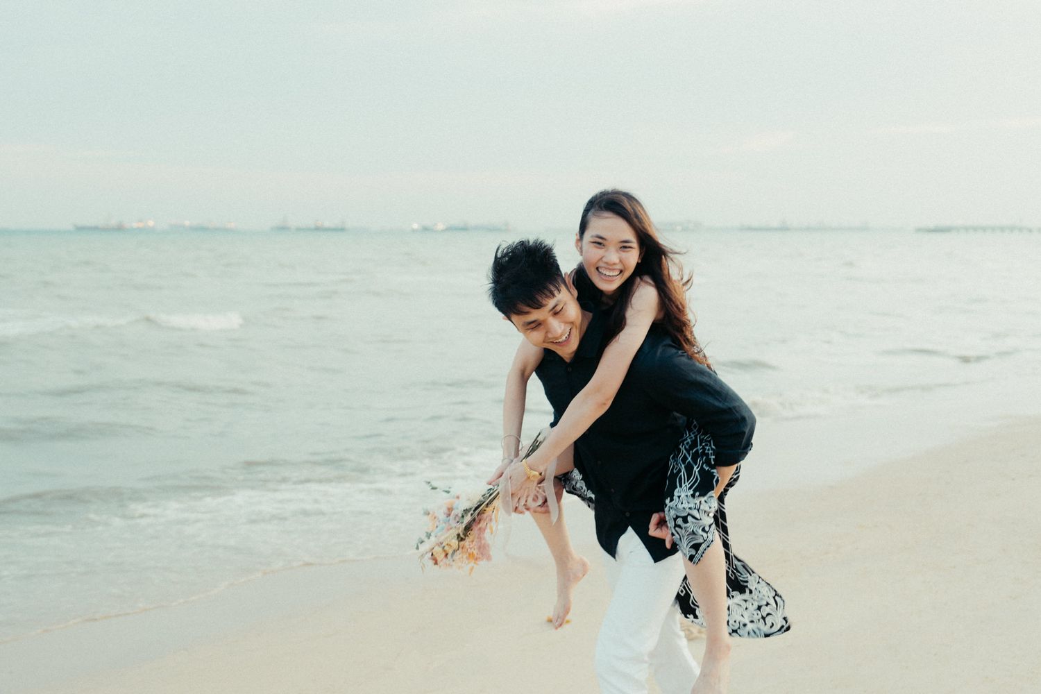 Couple playing and chasing each other by the ocean waves.