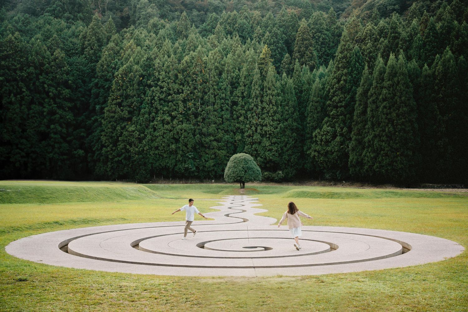 Modern spiral labyrinth pattern made of concrete paths in a green park setting.