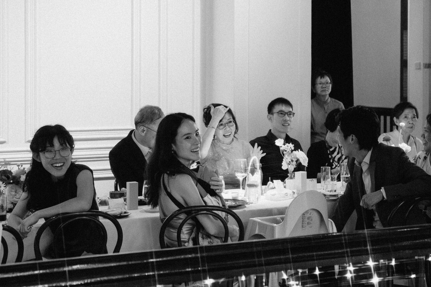Black and white photo of guests laughing and socializing at a formal dinner banquet event.