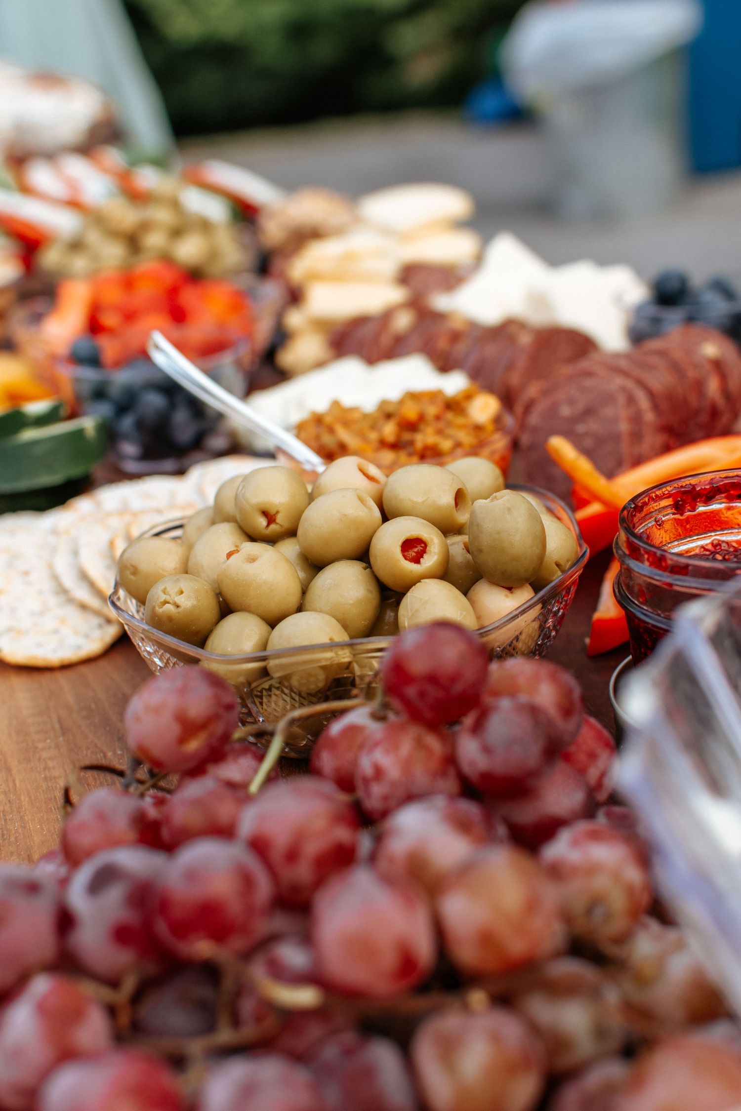 Fresh olives and red grapes arranged on a rustic charcuterie board create an appetizing display for entertaining.