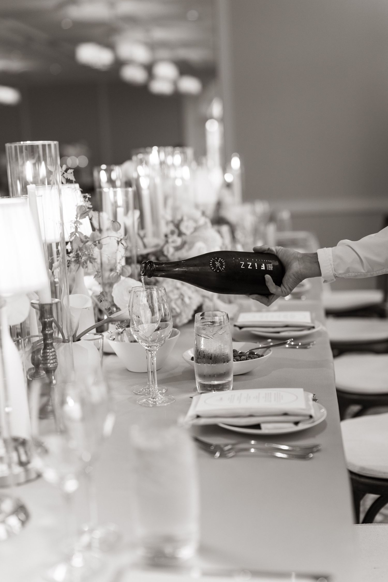 Elegant table settings with white linens and glassware create an upscale dining atmosphere in a modern restaurant.