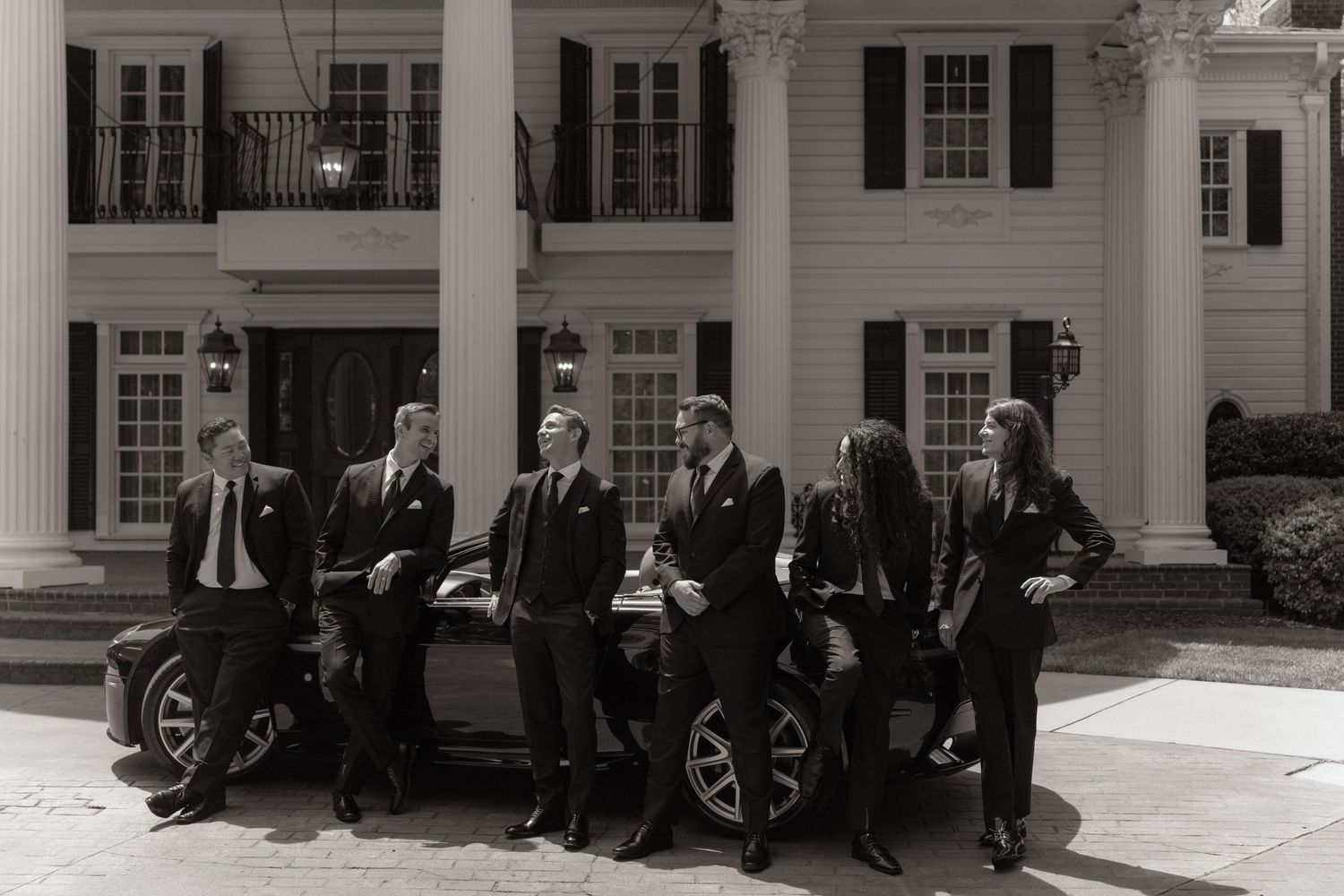 Classic wedding party group shot outside a white columned mansion building.