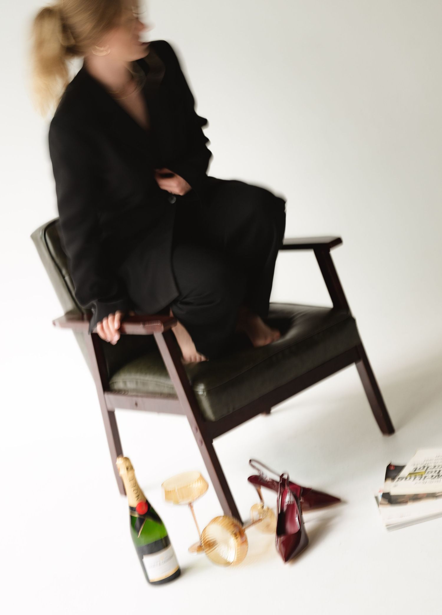 Fashion editorial sequence with black-suited figures lounging near wine bottles on white background.