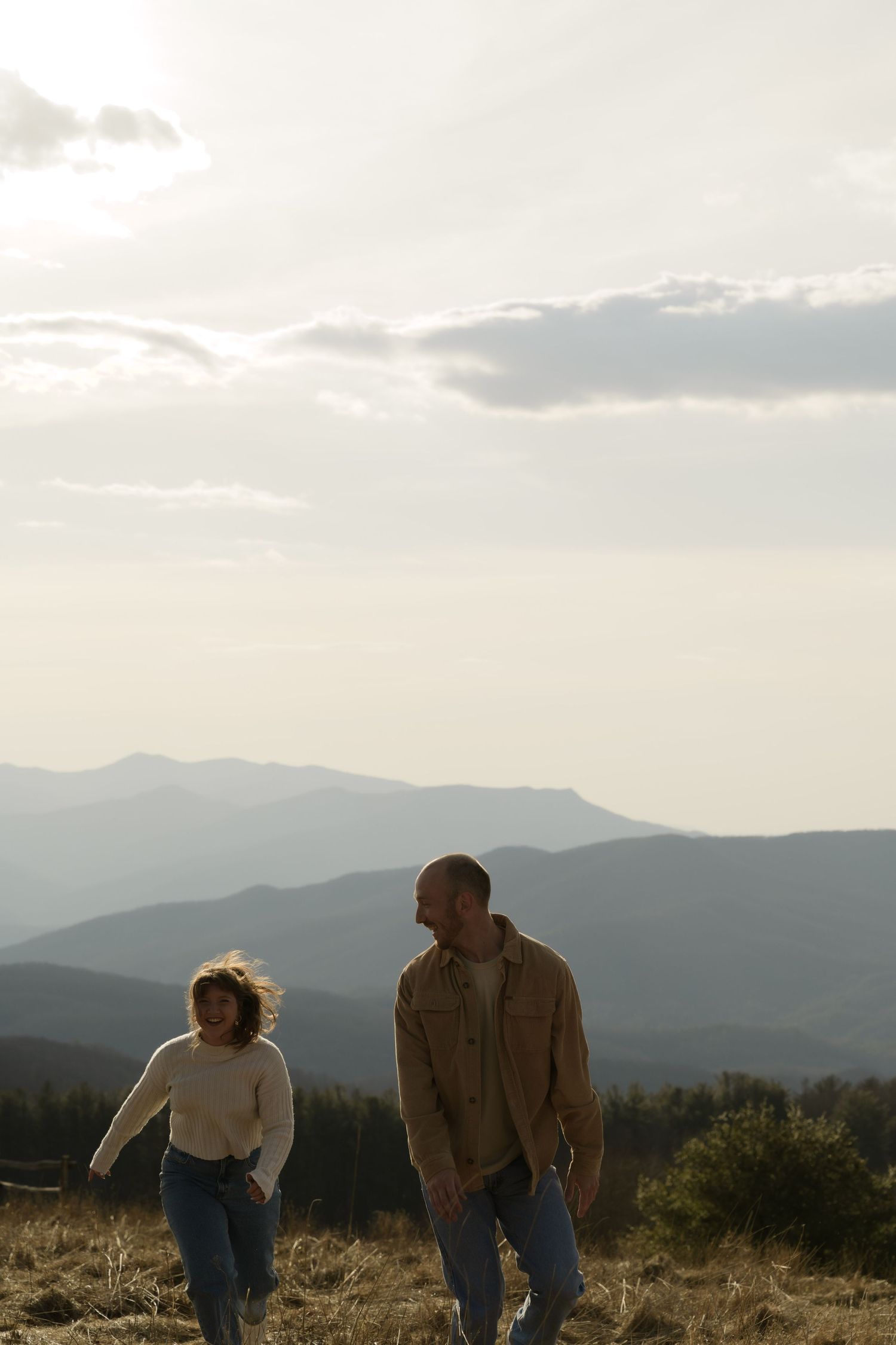 A couple enjoying a sunset together against a backdrop of misty mountain ranges.