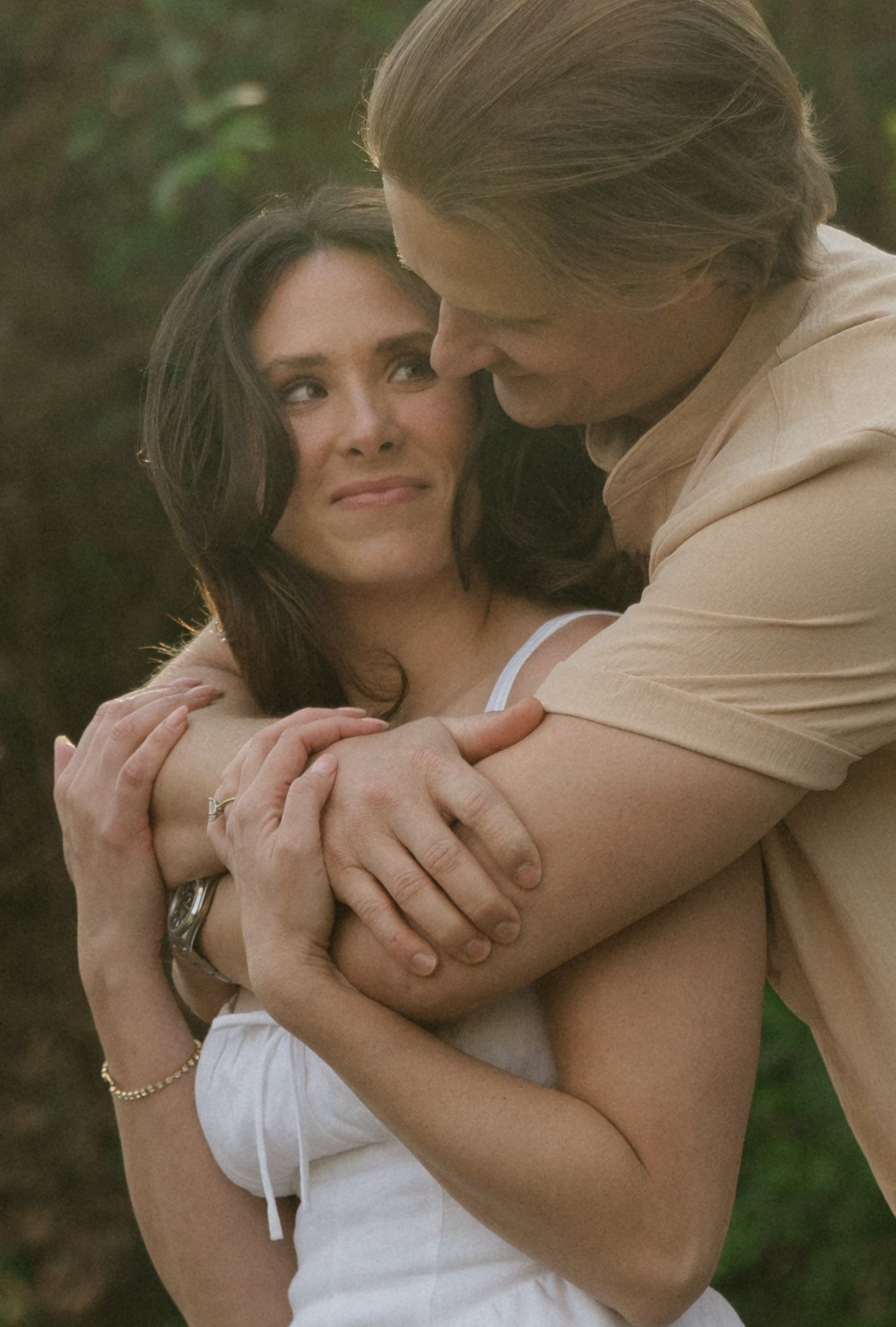 Intimate couple embracing in warm sunset lighting outdoors.
