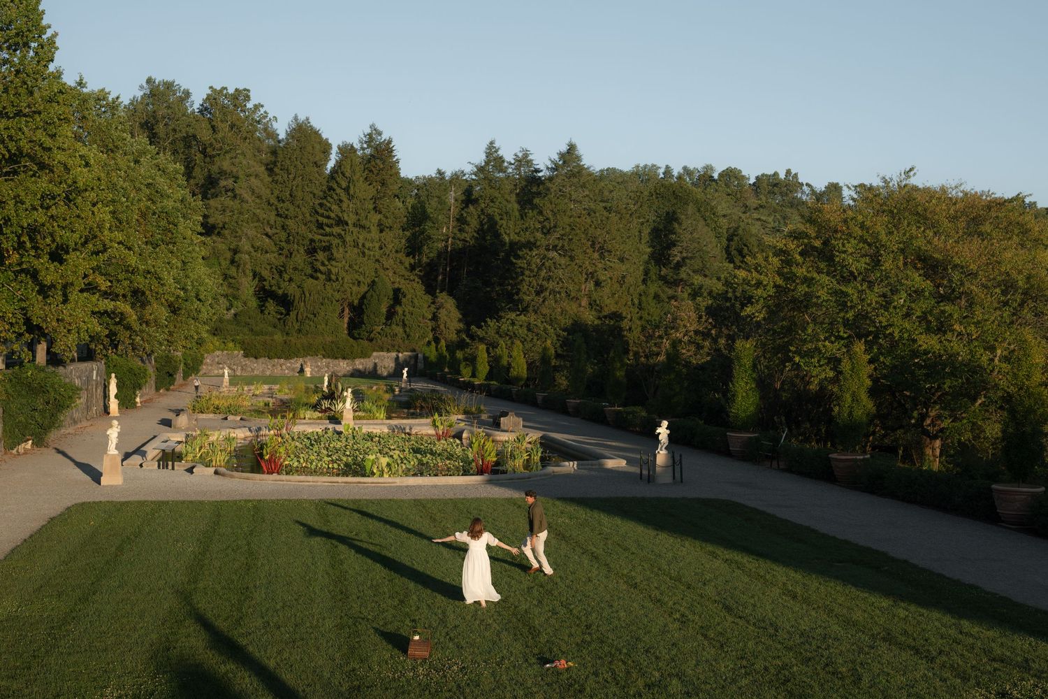 Scenic hilltop garden view with manicured lawn and trees in background.