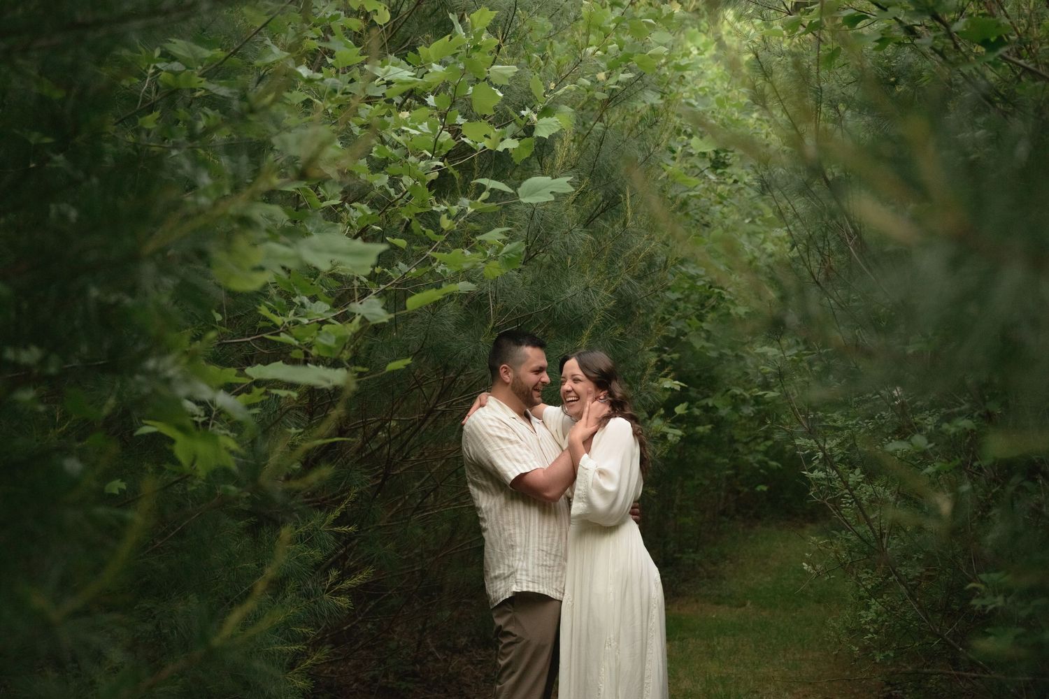 A romantic couple embracing in a lush garden setting during a photo session.