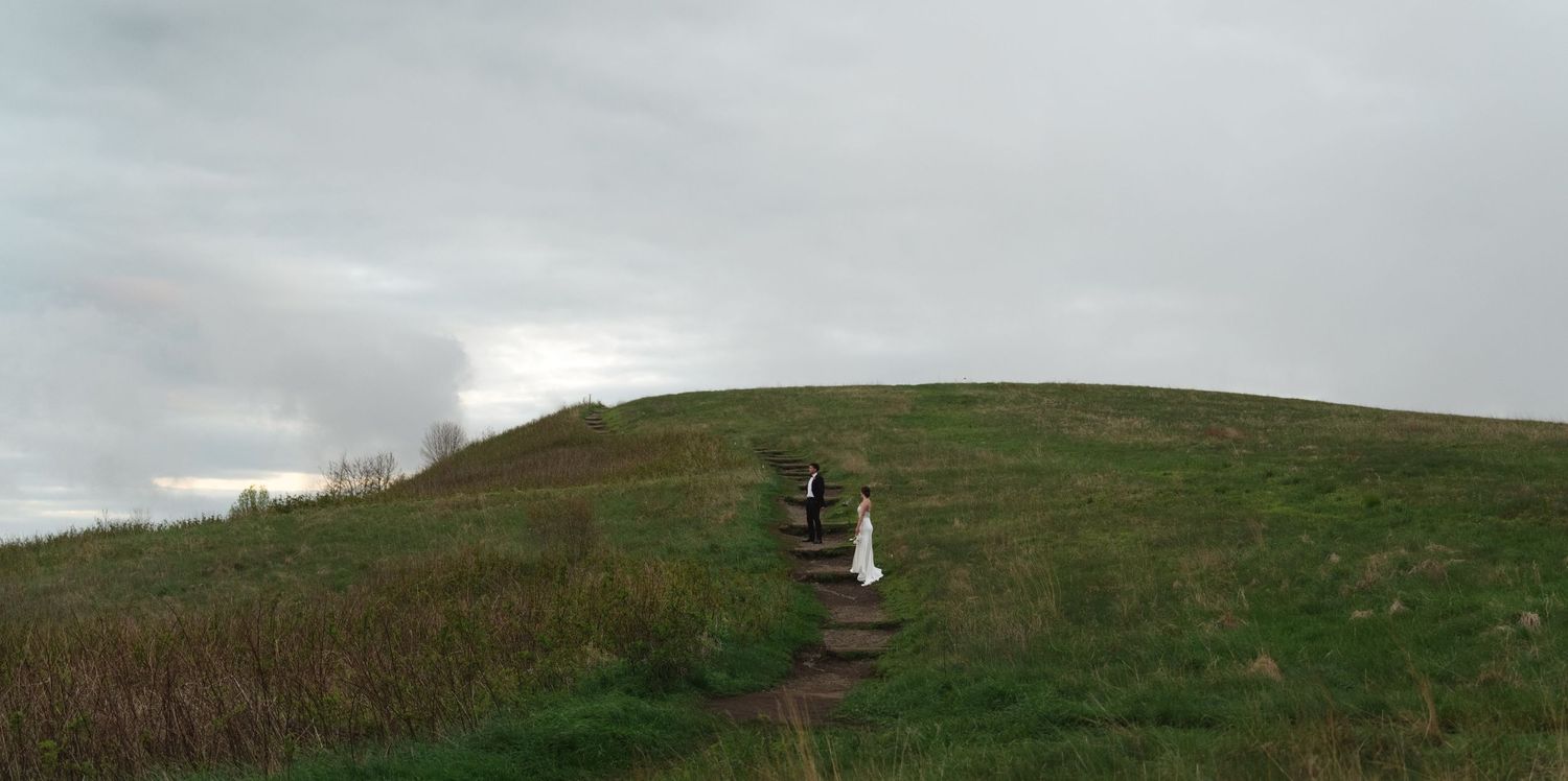 Rolling green hills under a cloudy sky with a winding path.