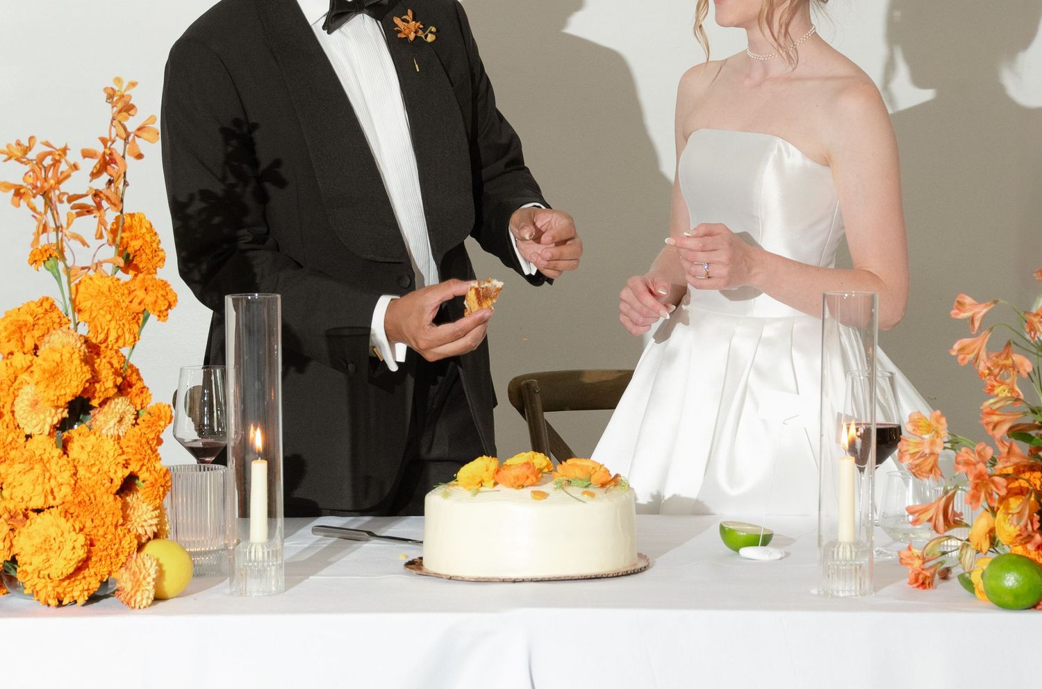 Wedding reception details showing orange floral centerpieces and white table settings.