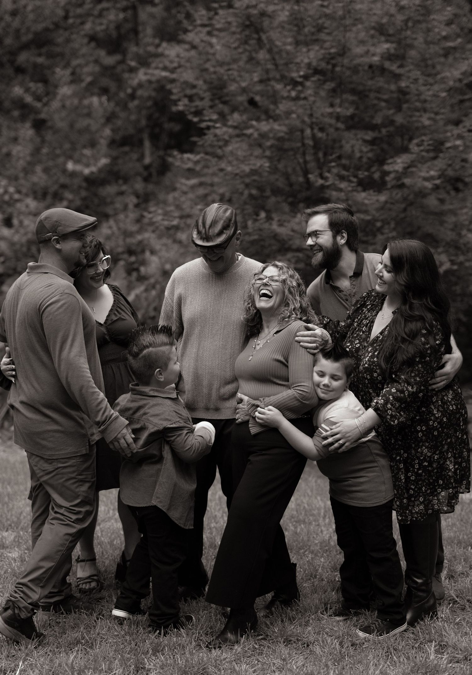 Group of friends sharing a heartfelt laugh together outdoors in a black and white photograph.