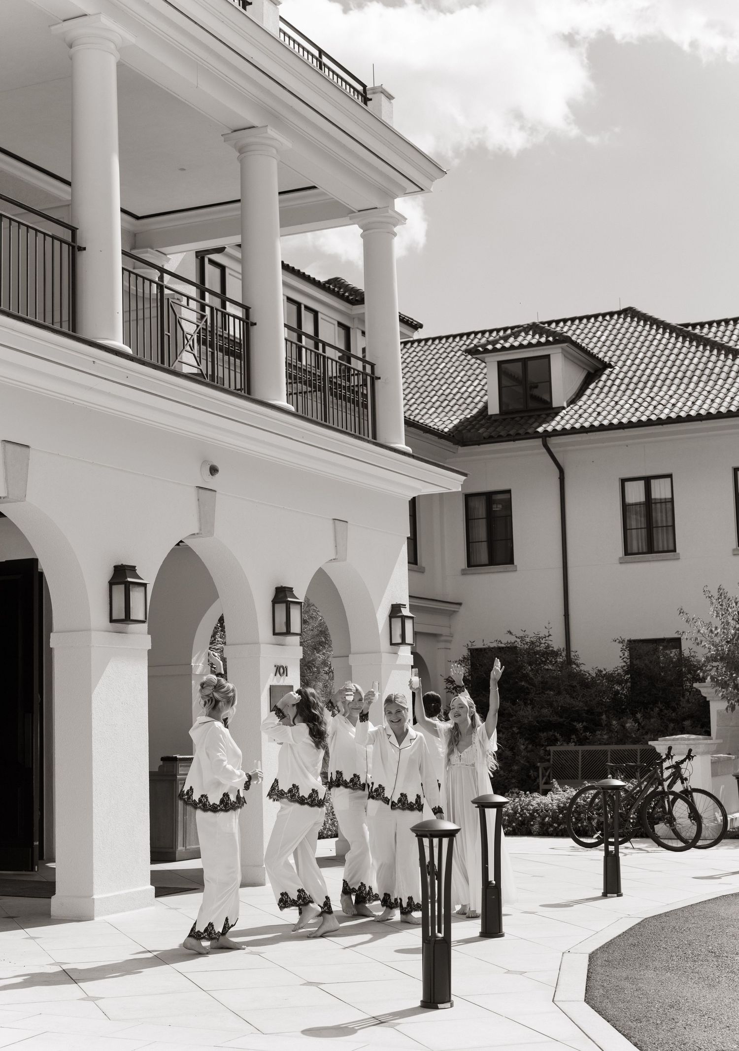 A black and white photograph shows a group in white uniforms standing under arched columns of a Mediterranean-style building.