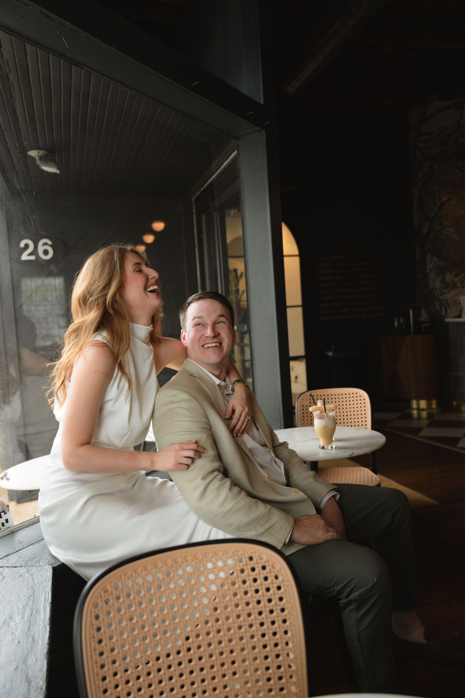 Couple laughing together at a cafe with outdoor seating and warm lighting.