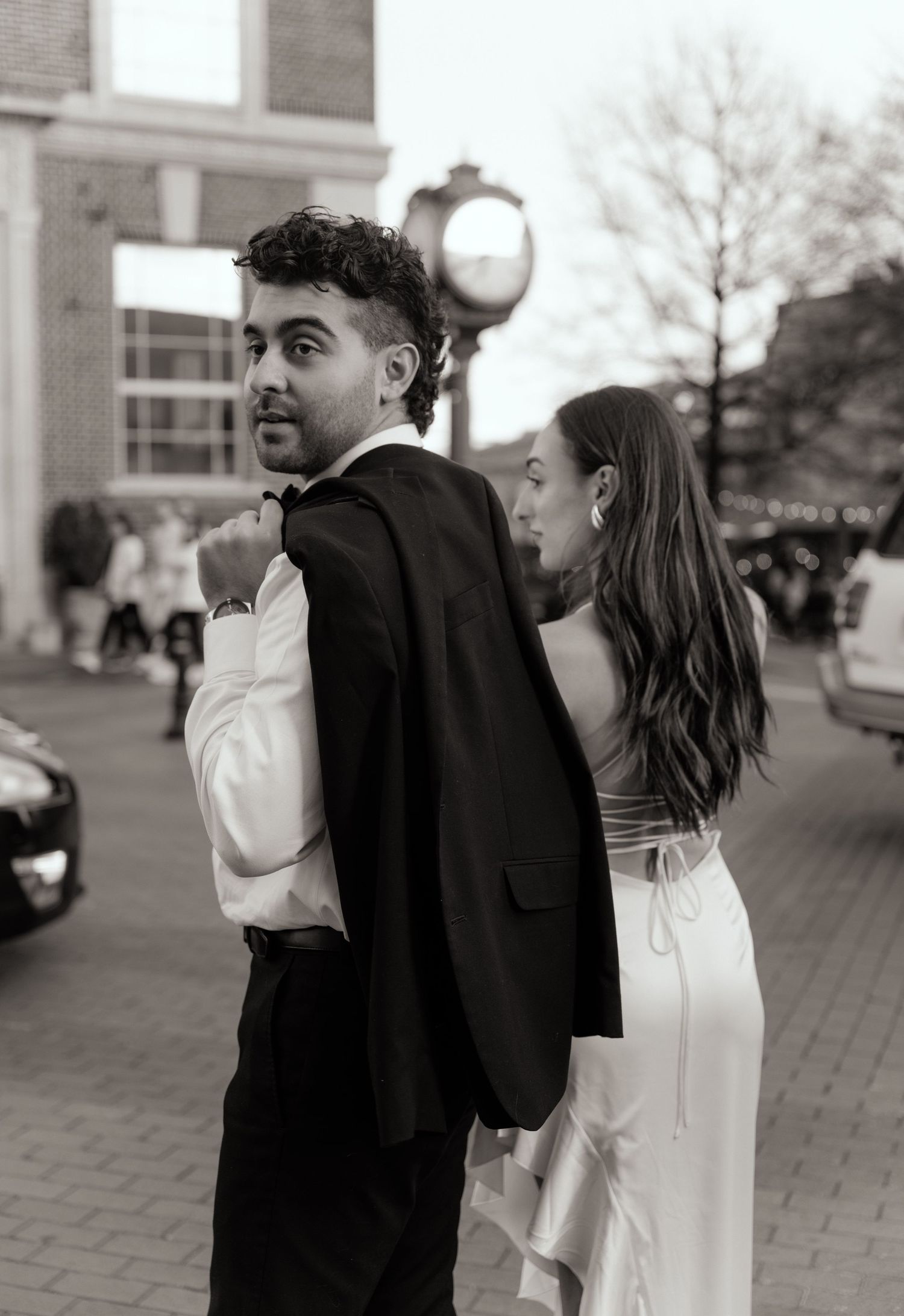 Black and white sequence of a couple dancing playfully on a brick paved street.