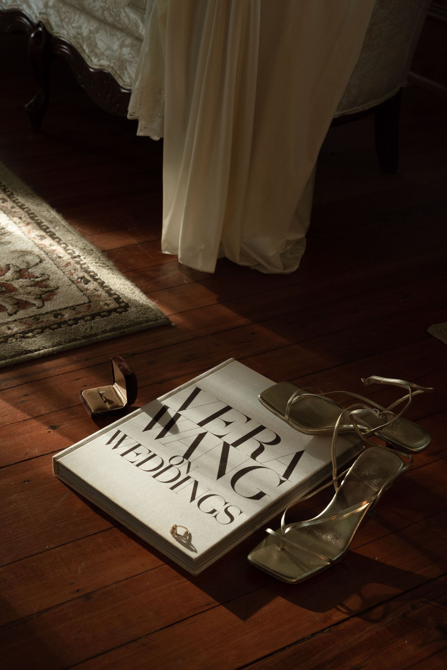 Wedding magazine and accessories artfully arranged on wooden floorboards in dramatic lighting.