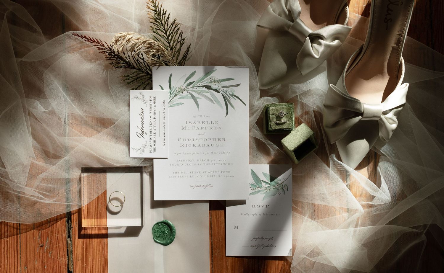 Wedding invitation flatlay with greenery and delicate fabric details.