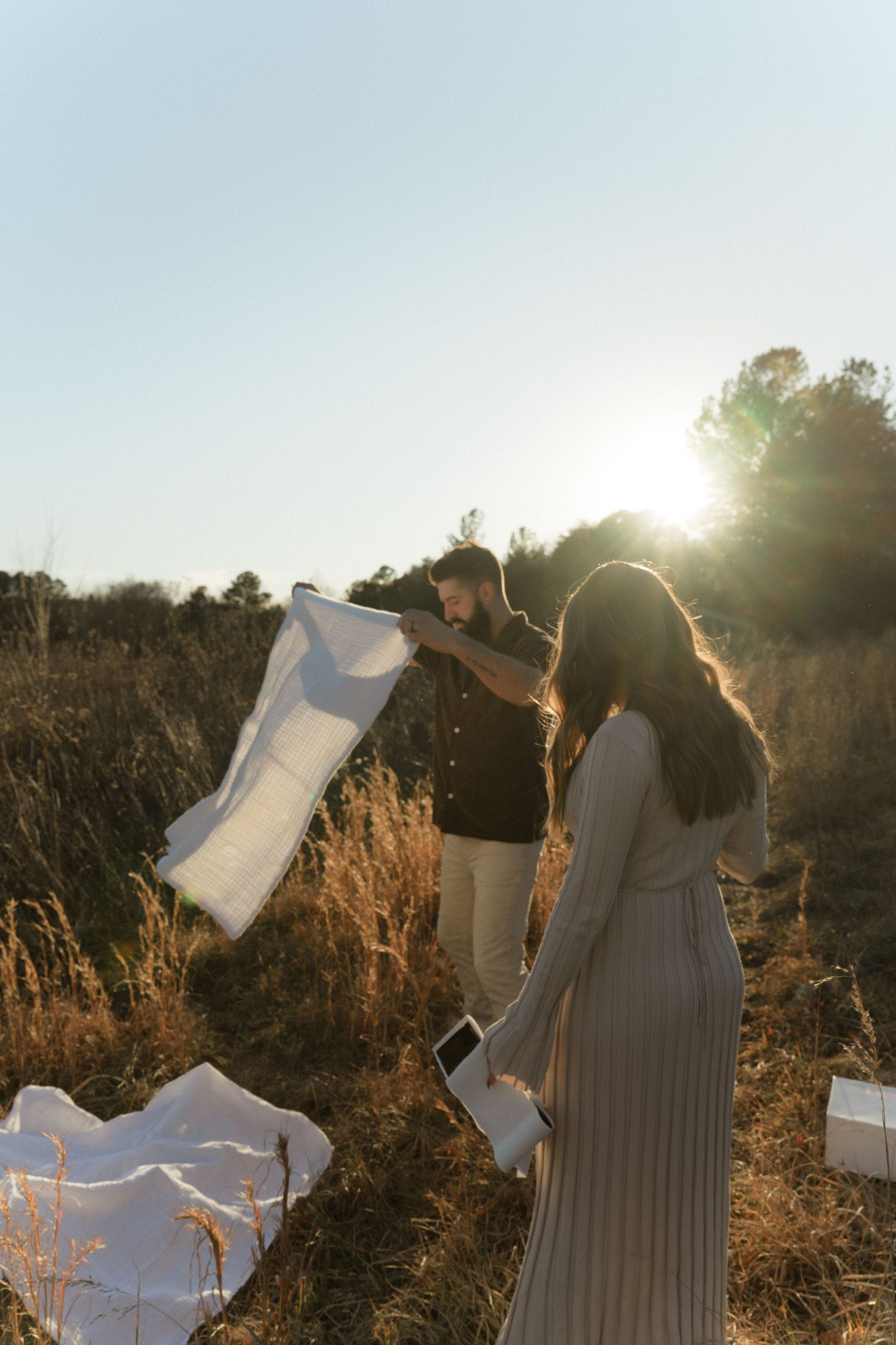 Silhouettes against sunset with flowing fabric creating dramatic movement in nature.