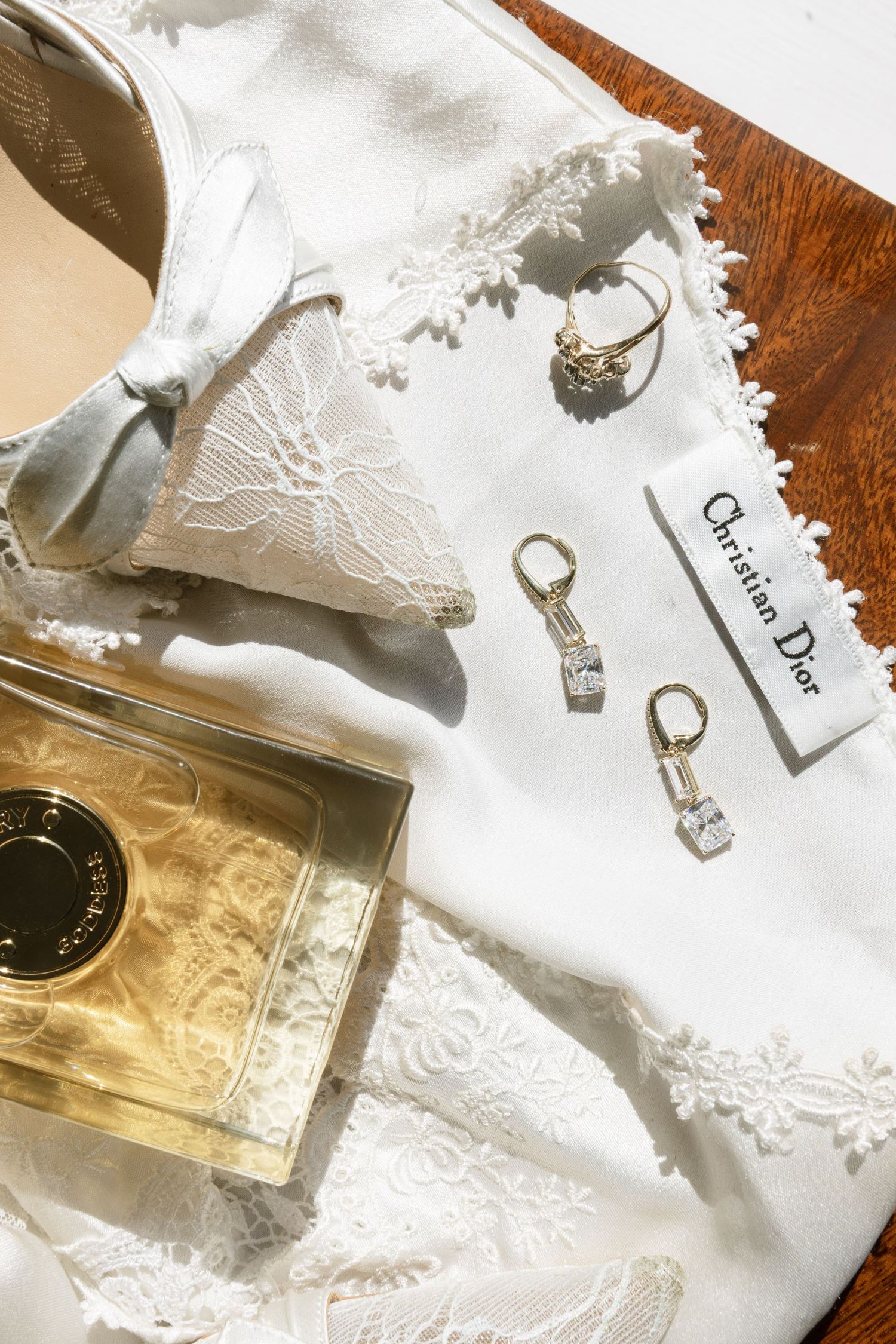 Luxury perfume bottles and jewelry arranged on white lace fabric with soft natural lighting.