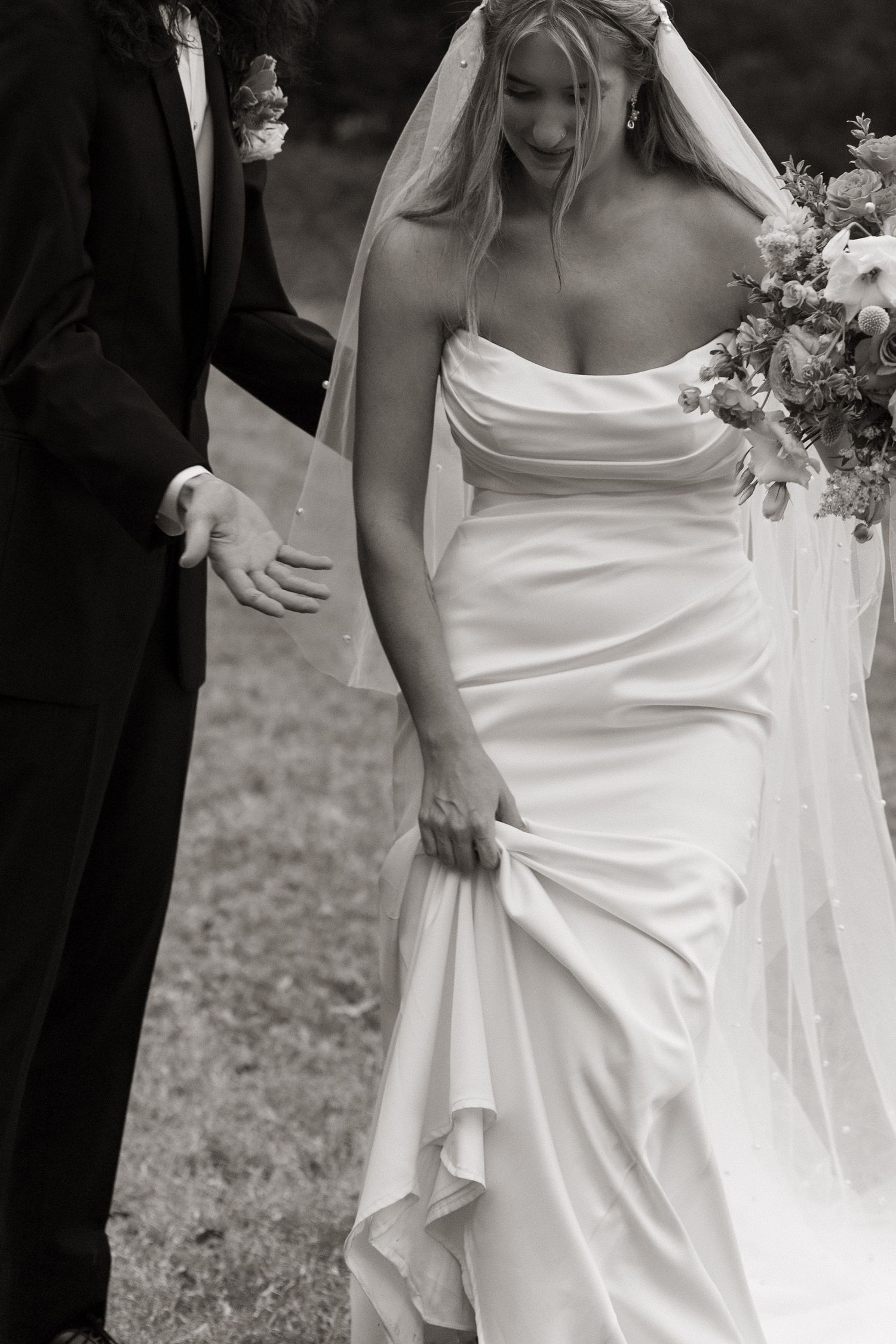 Black and white wedding photo showing couple in formal attire with bride wearing strapless gown and veil holding bouquet.