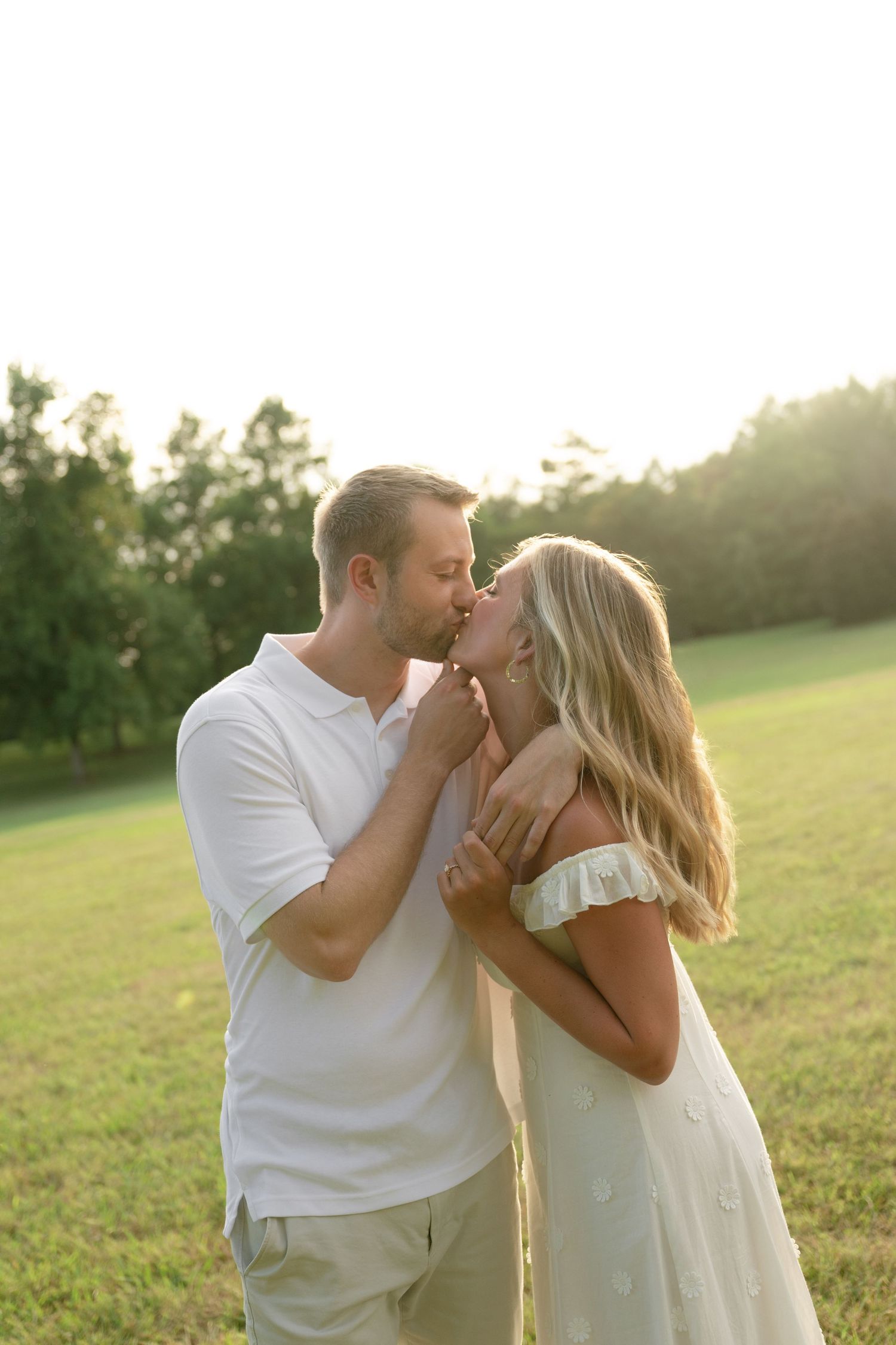 Sun-drenched couple sharing romantic moments in a golden field at sunset.