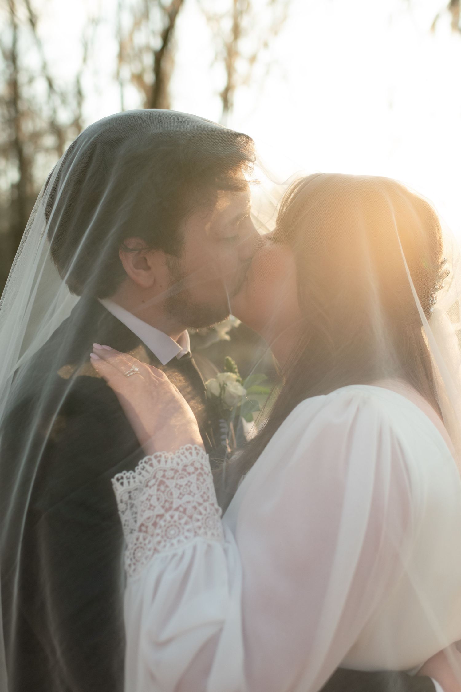 Romantic sunset wedding portrait with soft golden light filtering through a veil.