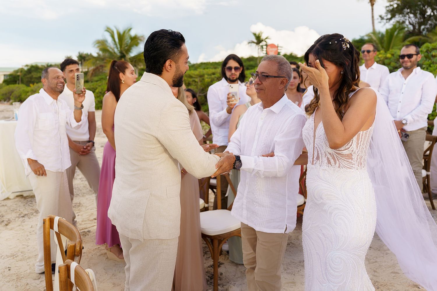 Emotional beach wedding ceremony with bride and groom exchanging vows surrounded by guests in tropical setting.