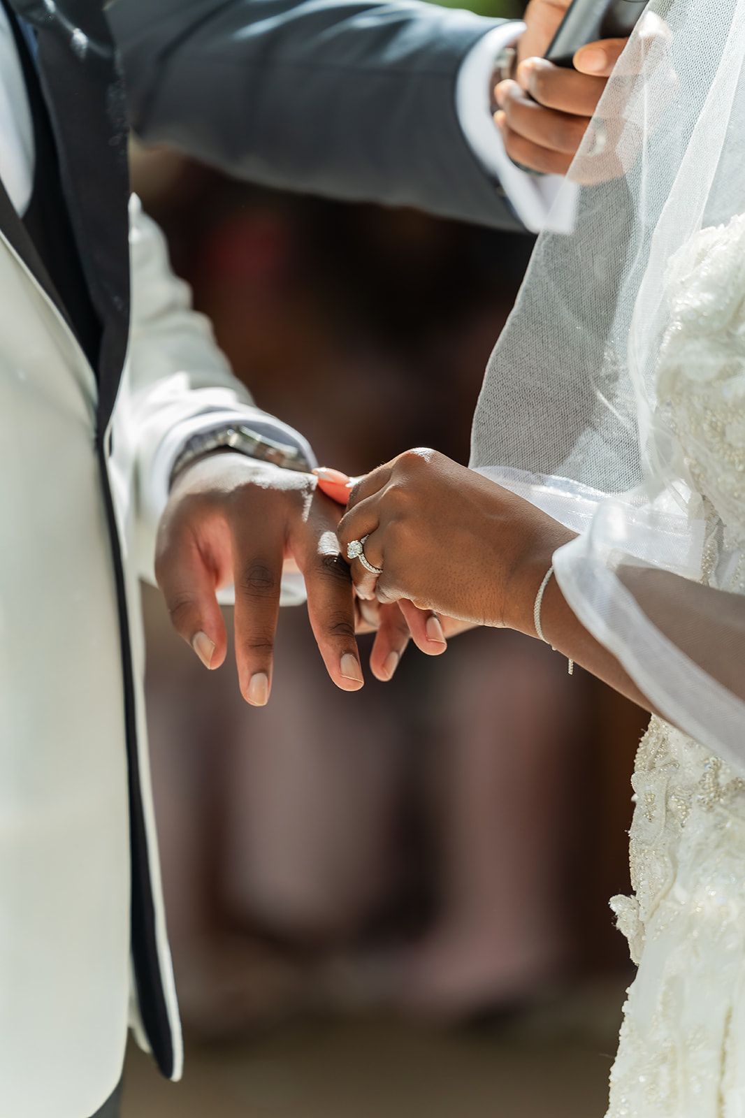 Bride places wedding ring on grooms finger during an outdoor wedding ceremony.