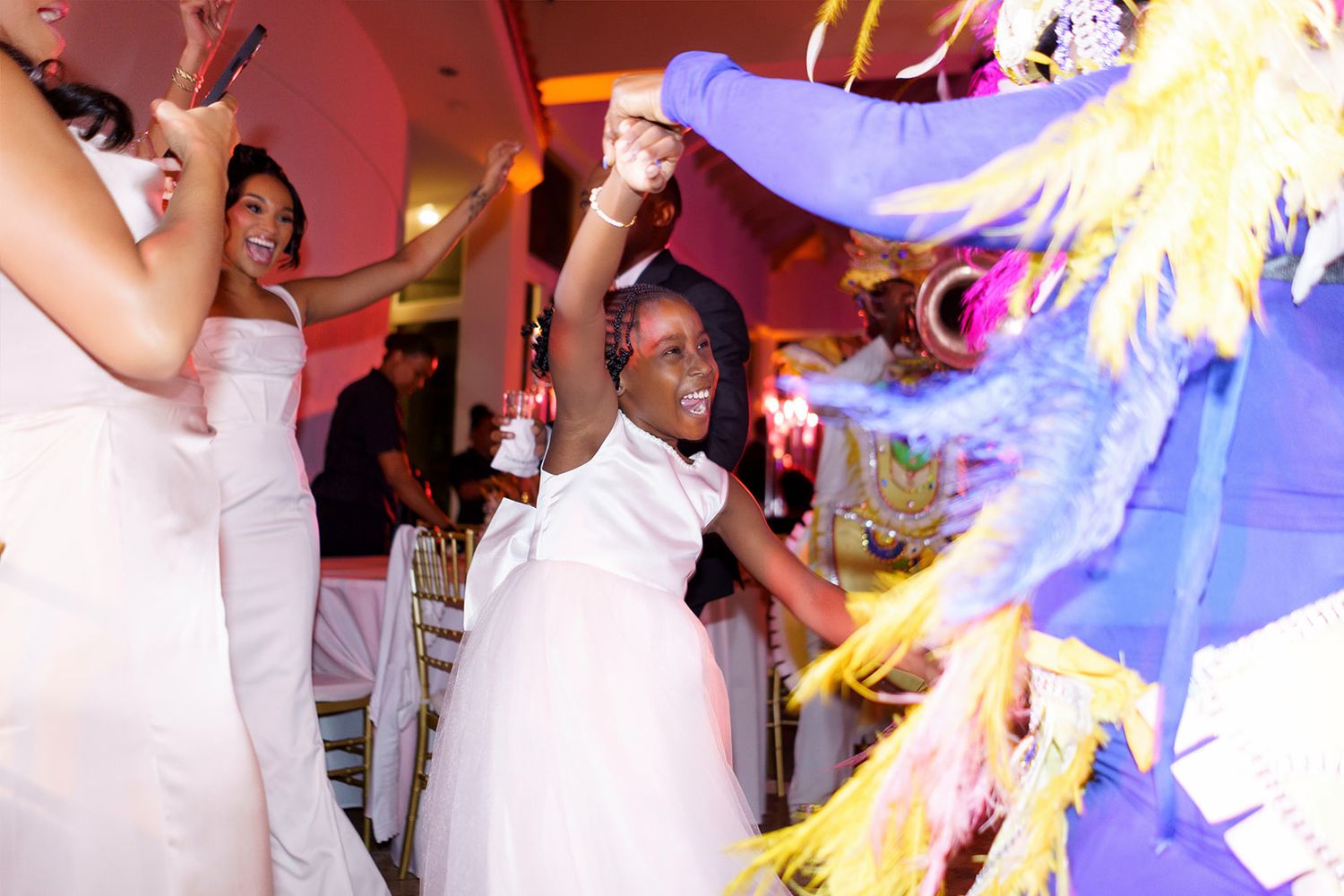 Young flower girl dancing joyfully at vibrant wedding reception celebration.