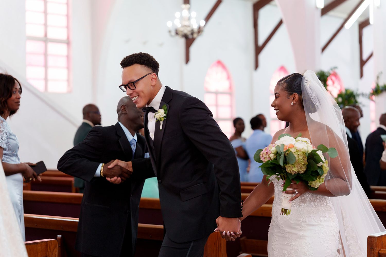 Bride and groom greeting guest after wedding ceremony in white church.