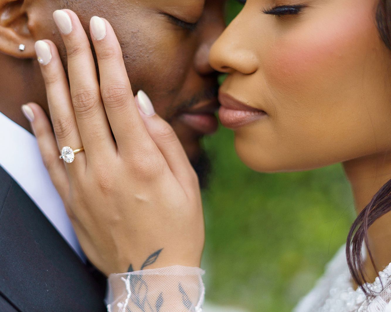 Close up shot of hands with engagement ring showing wedding jewelry details in outdoor garden setting.