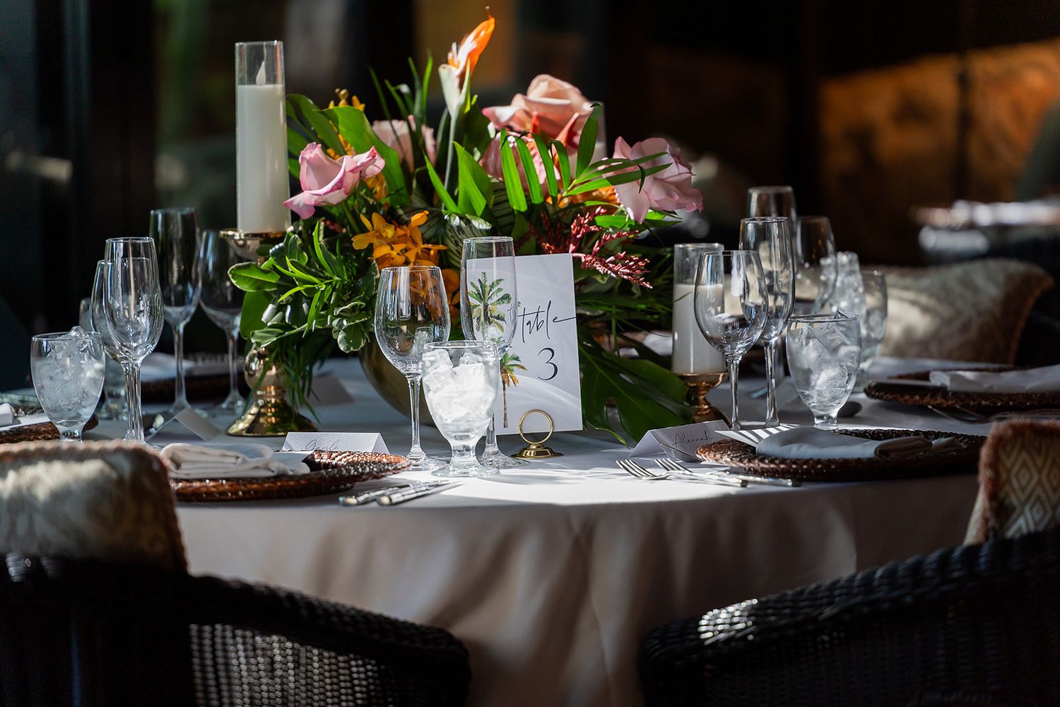 Elegant wedding reception table with floral centerpiece, champagne flutes, and table number 3 card.