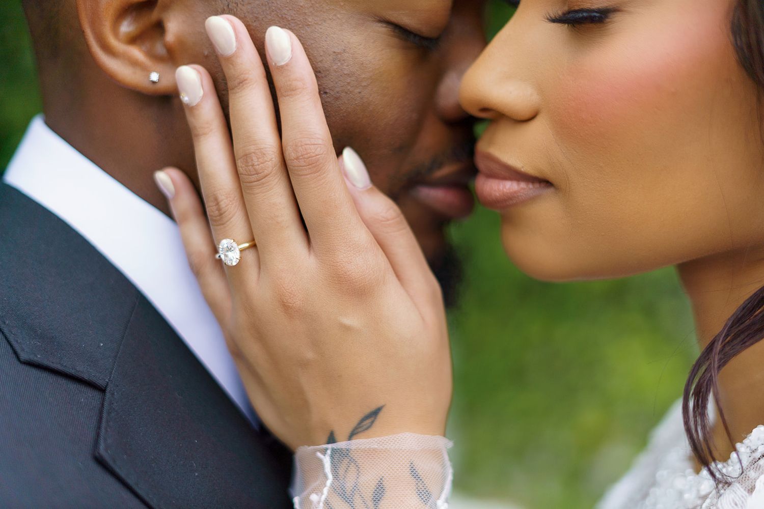 Close-up of a couple sharing a romantic kiss, showcasing a stunning diamond engagement ring on the bride's hand.