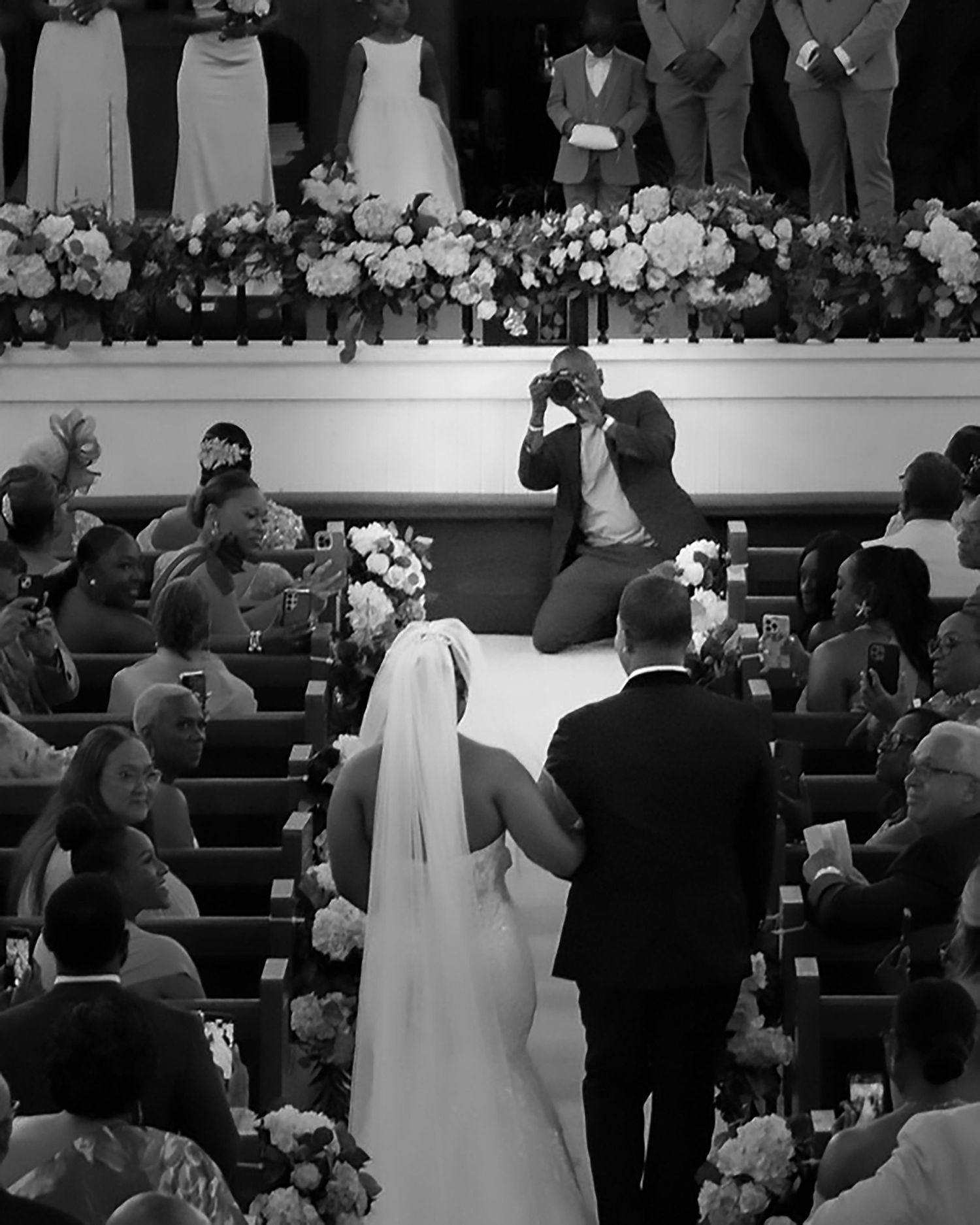 Black and white photo of a bride and groom walking down the church aisle during their wedding ceremony.