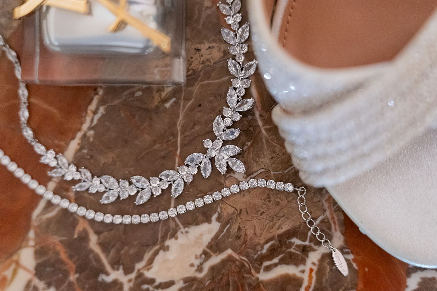 Elegant bridal accessories featuring crystal leaf hair vine, pearl necklace, and white beaded wedding heel.