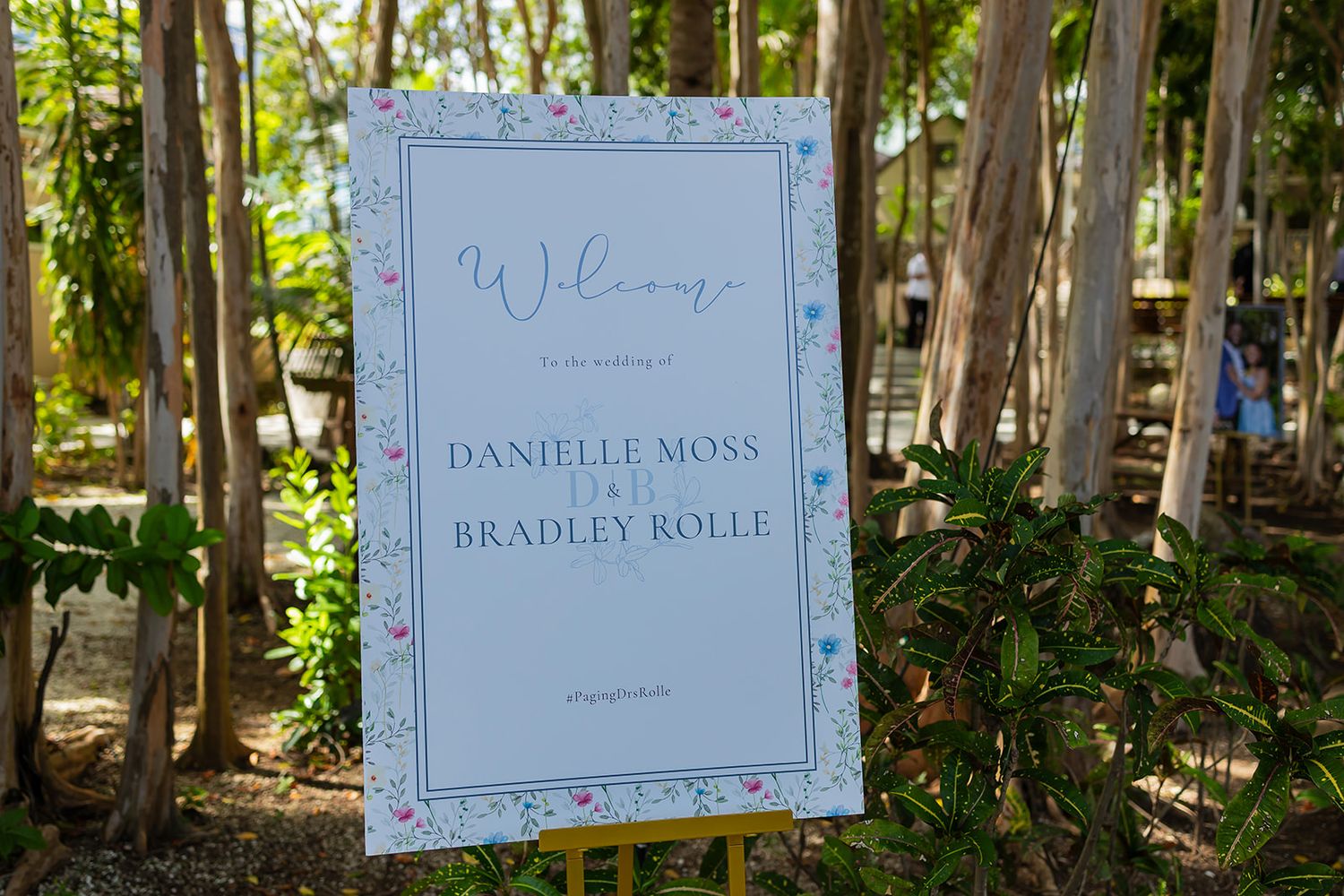Outdoor wedding welcome sign for Danielle Moss and Bradley Rolle surrounded by lush tropical greenery.