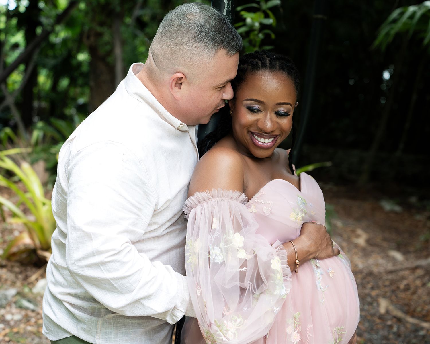 Maternity couple embracing in a beautiful garden
